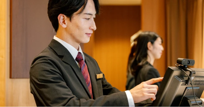 ホテルのフロントでノートパソコンを操作するスタッフ